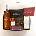 A curated gift box set from Biltong. featuring a bottle of Rosé, a jar of Traditional tomato jam, two bags of mixed nuts treats, and Basilei chocolate milo fudge on a plain white background.