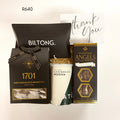 A gift set containing a Biltong box, a Wedgewood Angels chocolate and macadamia nougat, nougat biscuits, Plato caribean mocha, and a thank you card on a white background.
