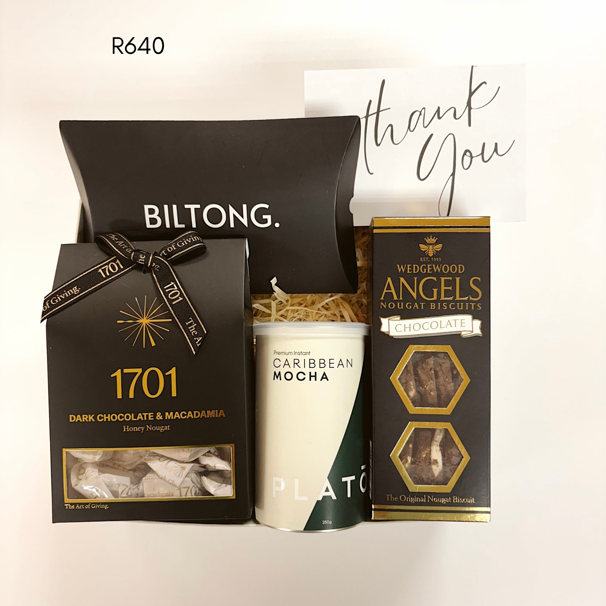 A gift set containing a Biltong box, a Wedgewood Angels chocolate and macadamia nougat, nougat biscuits, Plato caribean mocha, and a thank you card on a white background.